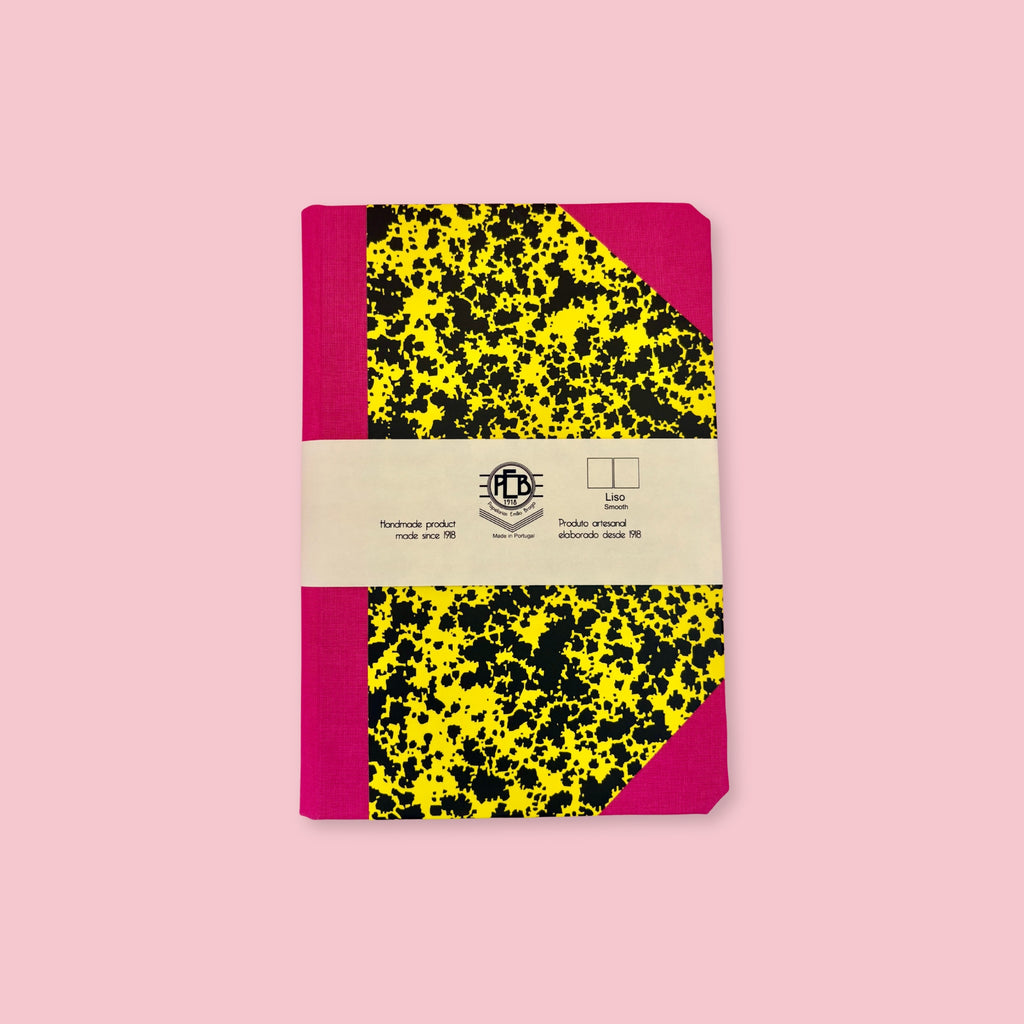 Pink and yellow patterned notebook with paper band, shown against a pink background.