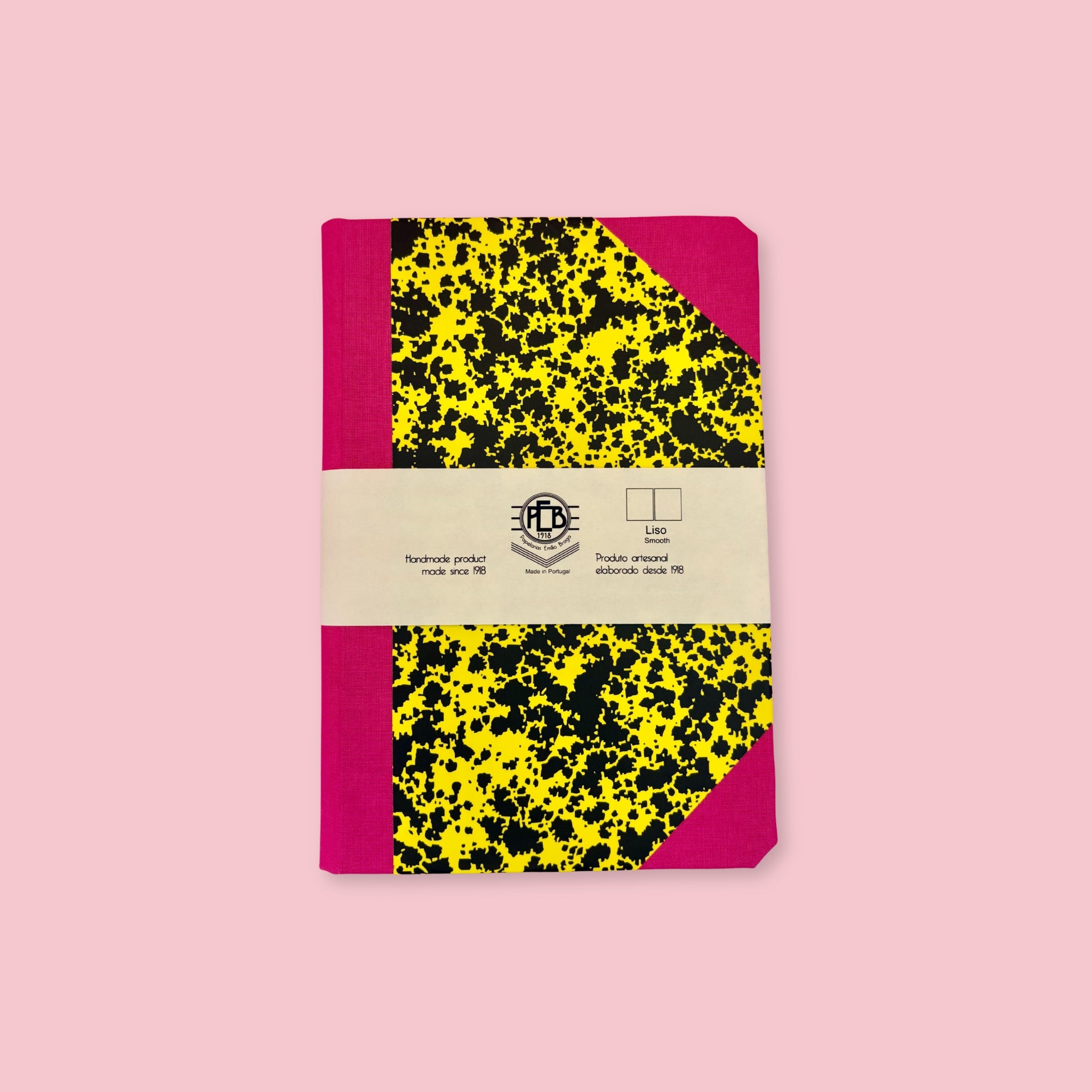 Pink and yellow patterned notebook with paper band, shown against a pink background.