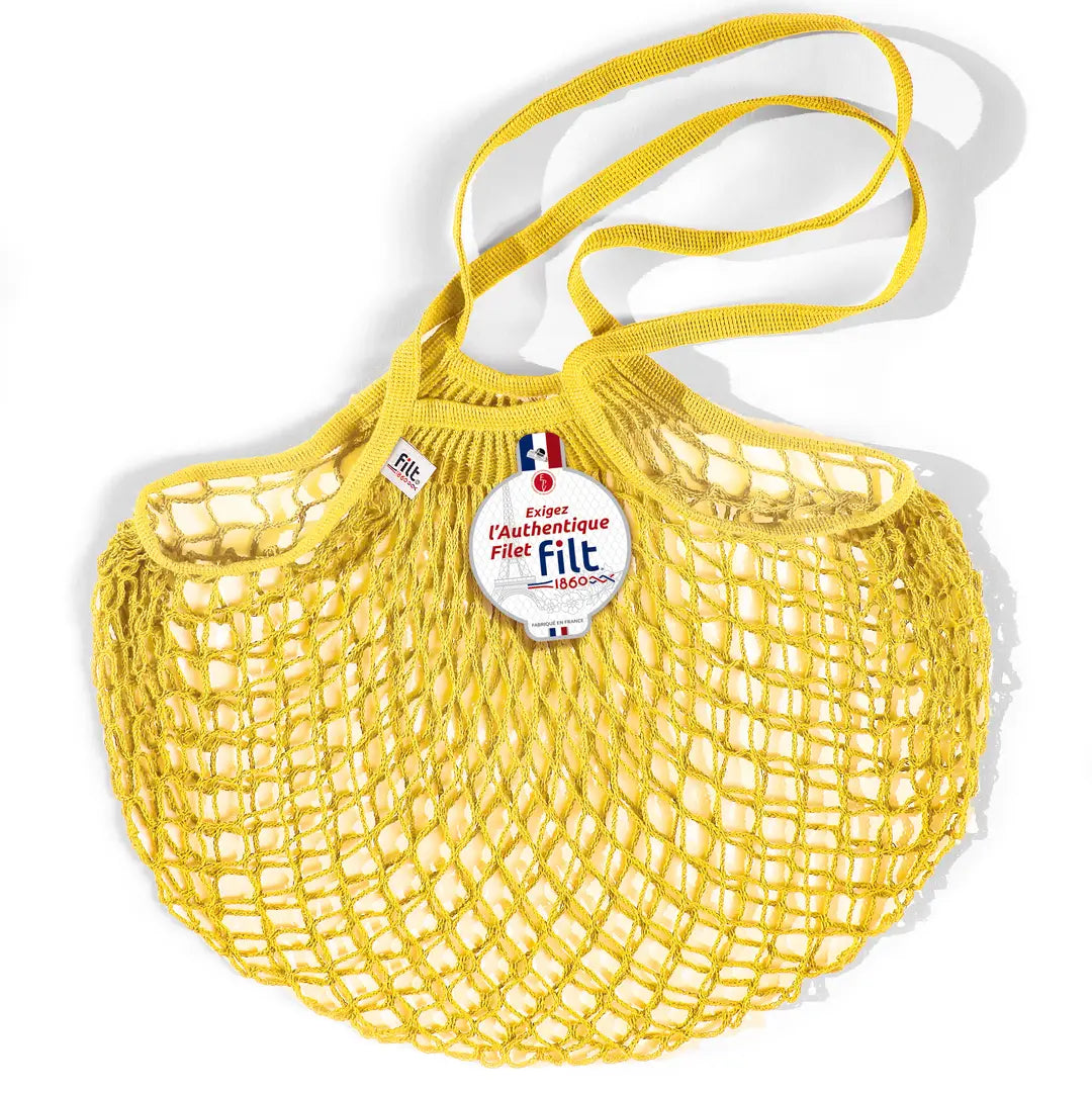 Filt French market mesh tote bag in yellow with long handles and round brand tag, shown on a white background.