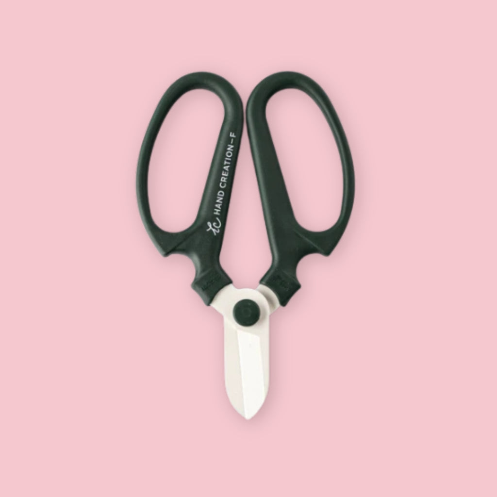Hand Creation flower shears in moss green with white blade tip on a pink background