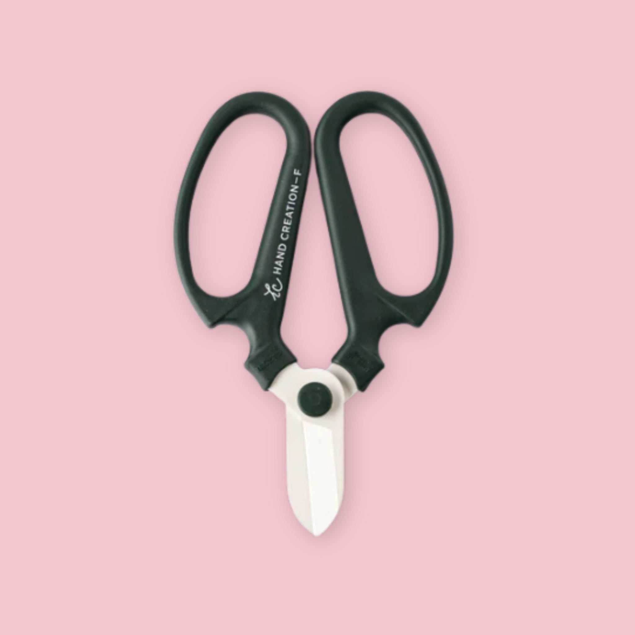 Hand Creation flower shears in moss green with white blade tip on a pink background