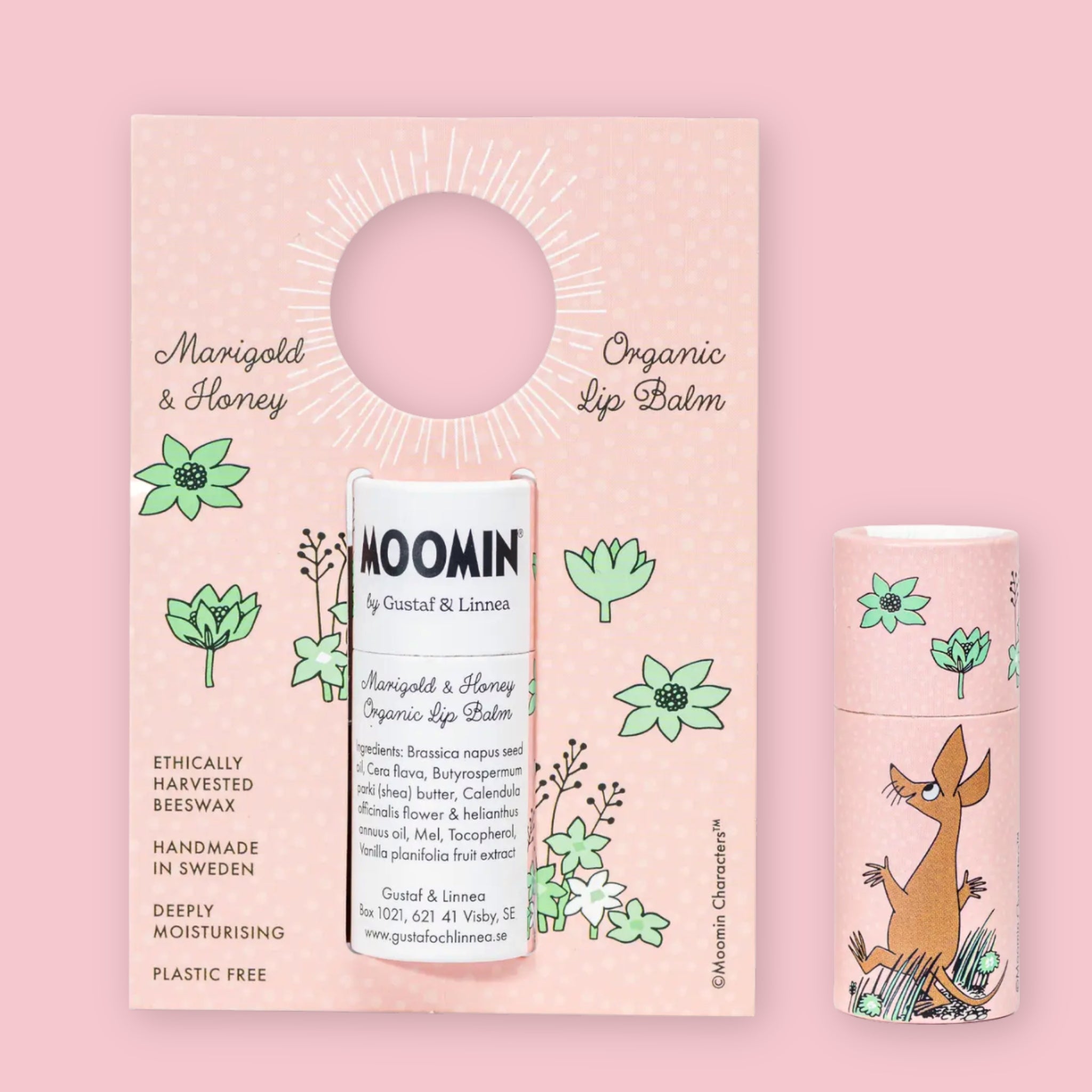 Marigold & Honey Moomin Organic Lip Balm on its illustrated cardboard display card with floral details, next to a second sealed tube showing the Sniff character design, against a pink background