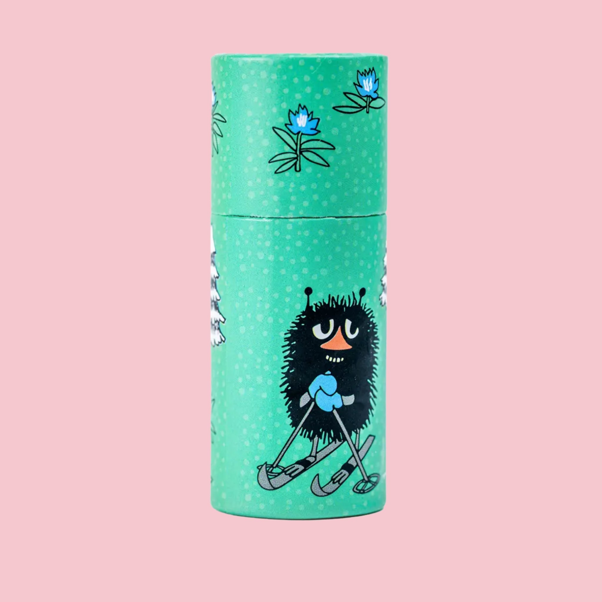 Mint Moomin lip balm tube illustrated with the Stinky character skiing on green packaging with blue floral accents, against a pink background
