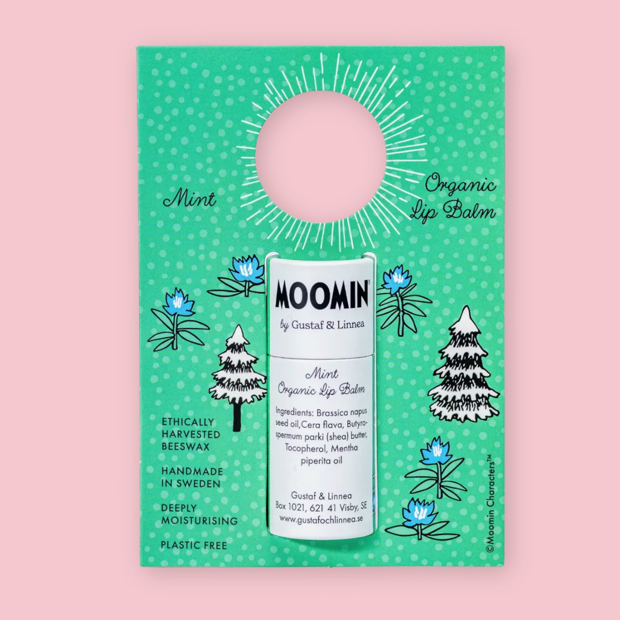 Mint Moomin Organic Lip Balm on its illustrated cardboard display card with pine tree and floral details, against a pink background