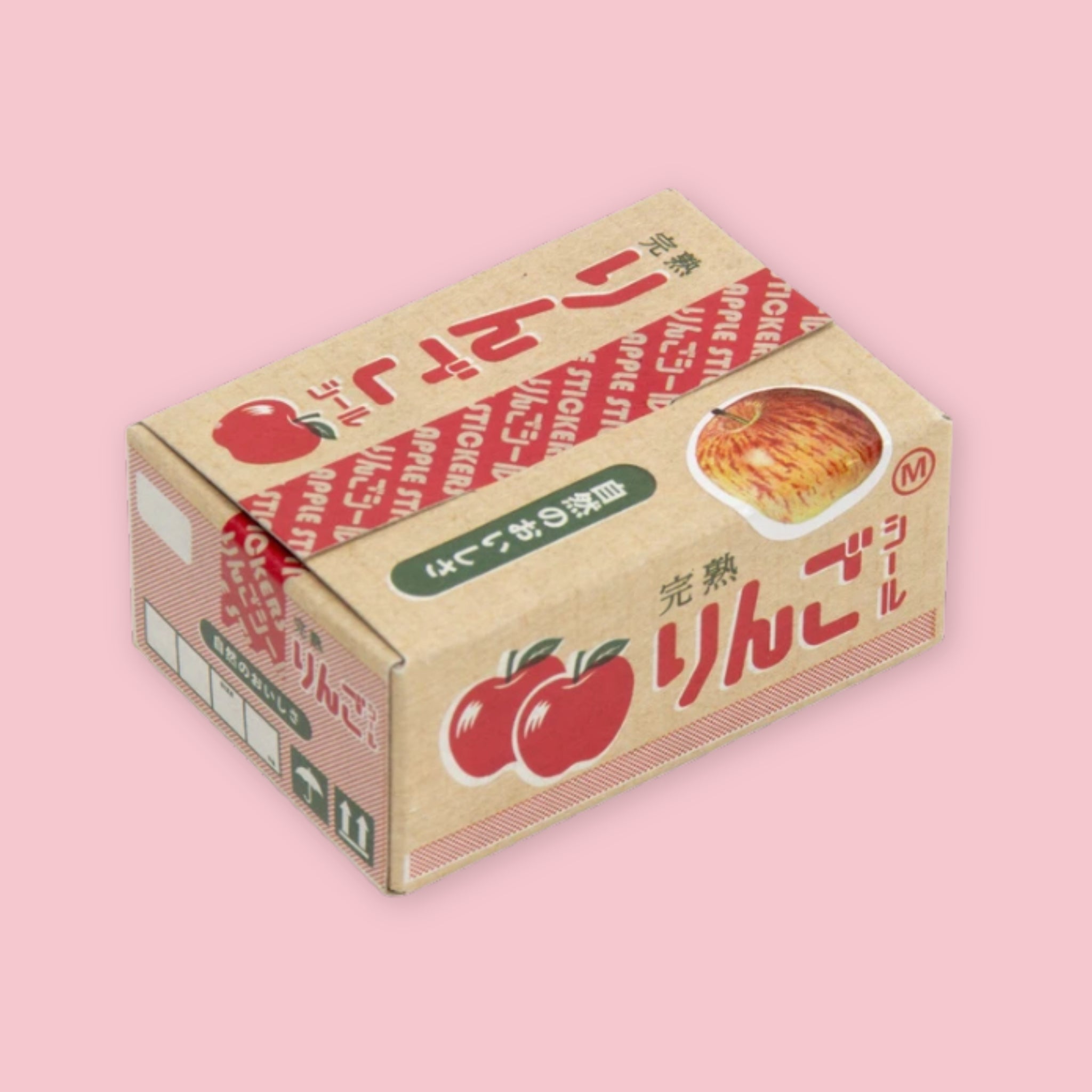 Box of Hako stickers designed to resemble a vintage Japanese apple crate, with kraft brown packaging, red apple illustrations, Japanese text reading "ringo" (apple), and a realistic apple photo detail, on a pink background.
