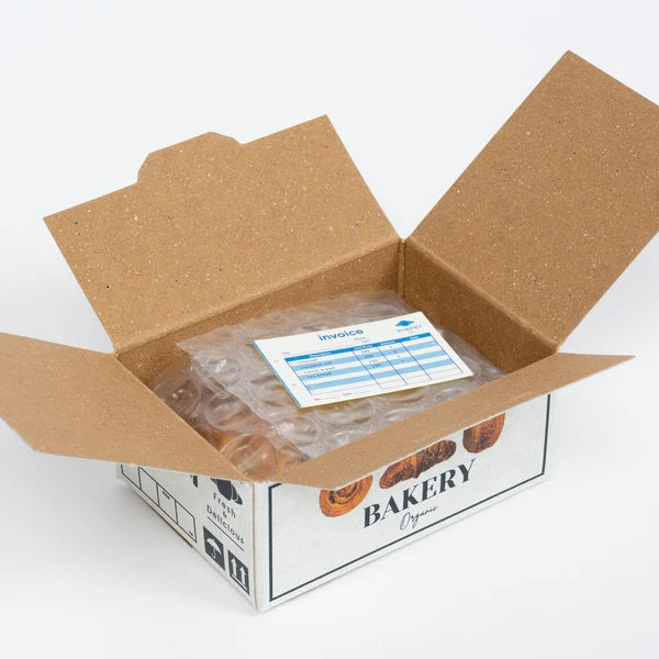 Open cardboard box with bakery items and an invoice on a white background
