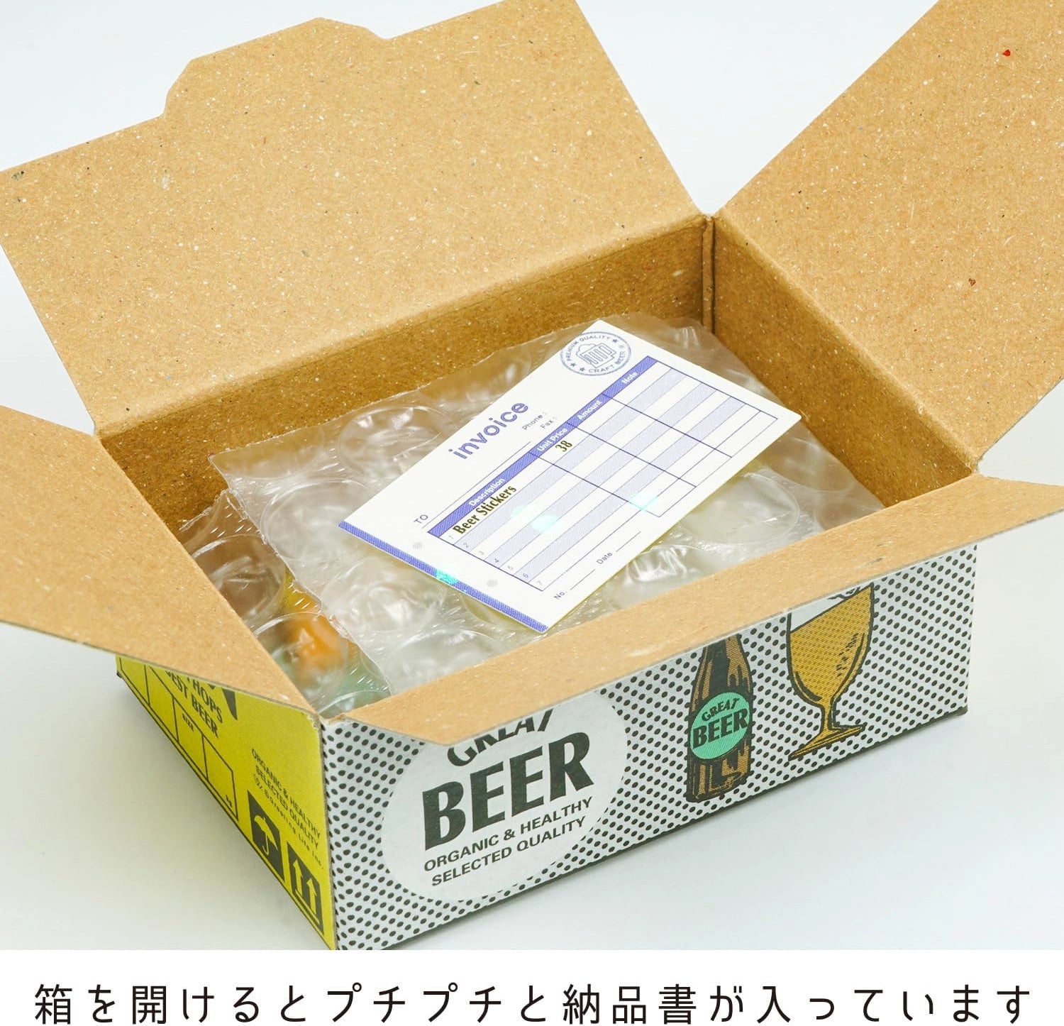 An open kraft cardboard box with a printed front panel showing beer-themed graphics and text, containing bubble wrap and an invoice card.