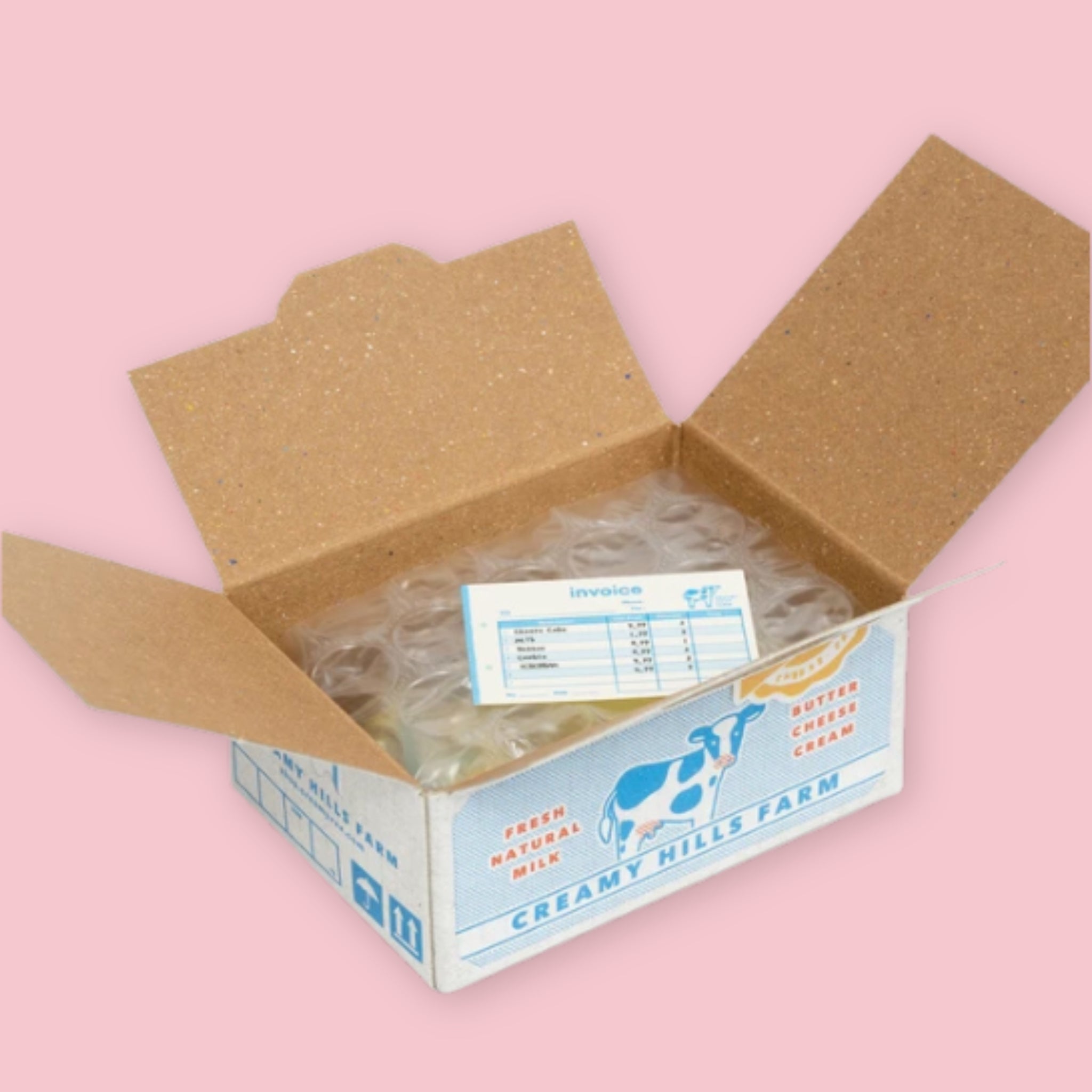 Open Hako sticker box showing bubble-wrapped stickers and an invoice inside, with the white and blue Creamy Hills Farm dairy packaging visible on the exterior, on a pink background.