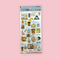 Japanese convenience store sticker sheet with snacks, drinks, onigiri, bento, and everyday items, shown against a pink background.