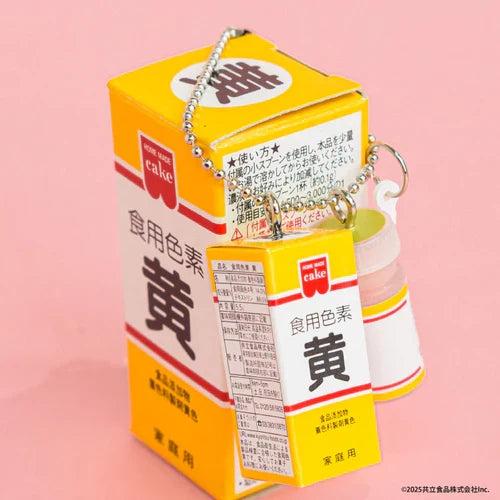 Miniature yellow Japanese food coloring box charm with matching cake-making accessories, shown on a pink background with a ball chain.