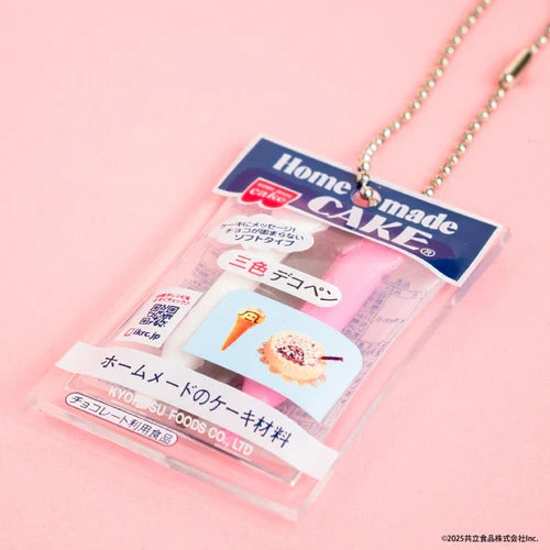 Miniature homemade cake kit charm with Japanese packaging, shown on a pink background with a ball chain.