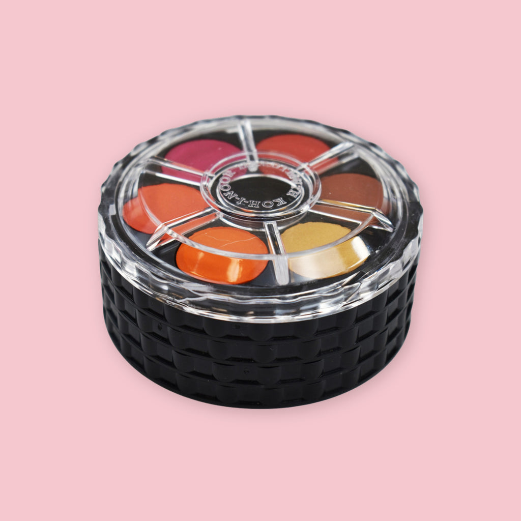 Koh-I-Noor Watercolor Wheel shown assembled and locked with clear mixing lid revealing orange-red color family tray on a pink background