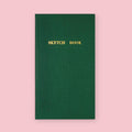 Green Kokuyo Sketch Book with gold lettering on a pink background