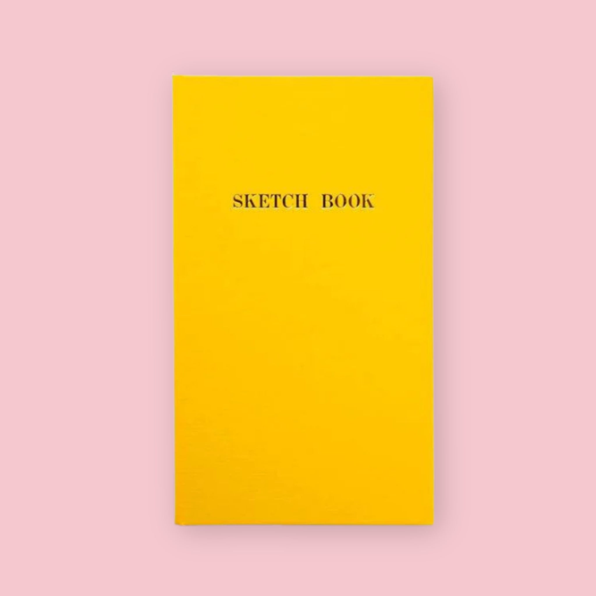 Yellow Kokuyo Sketch Book with gold lettering on a pink background