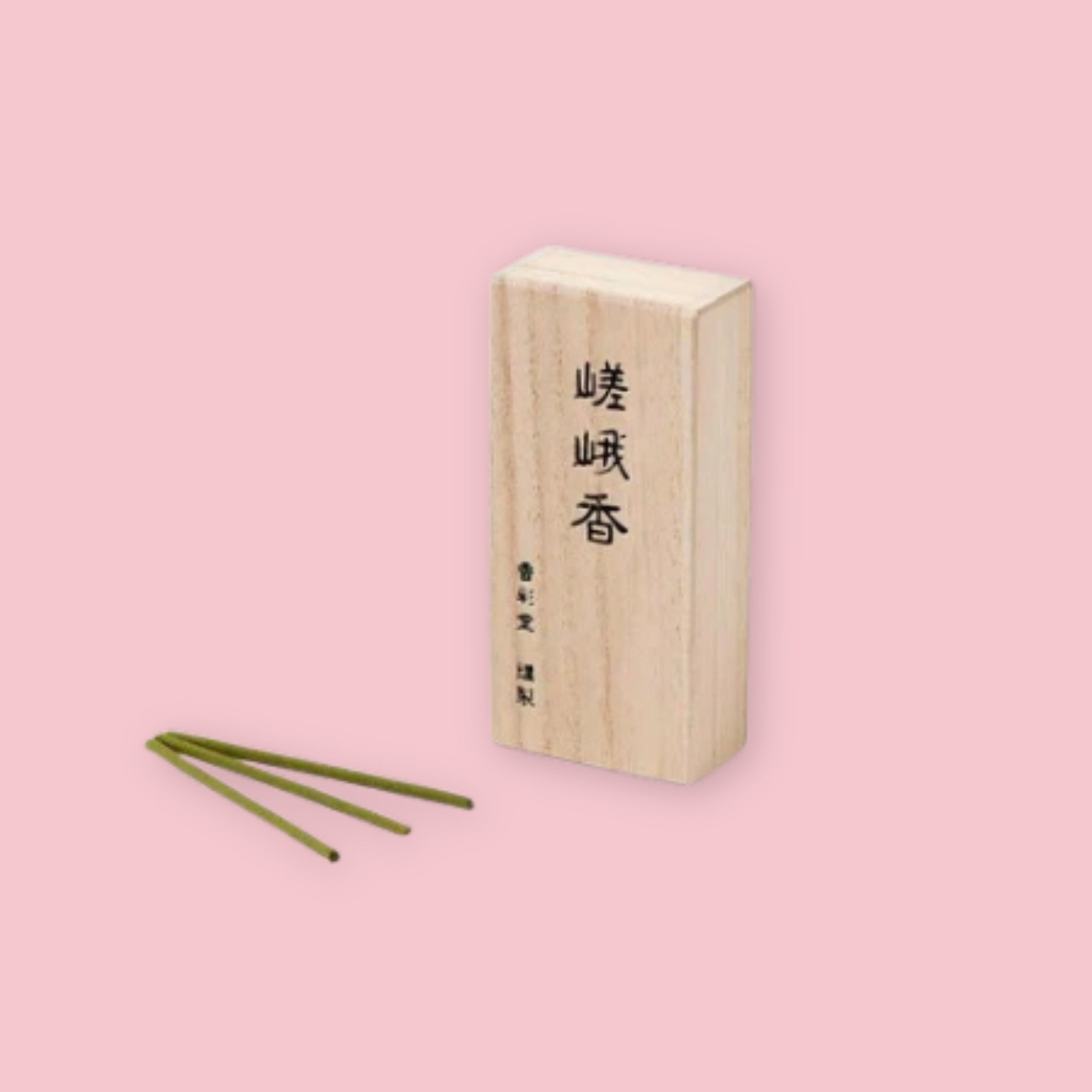Kousaido Morning Mist incense box with kanji lettering, shown beside three loose green incense sticks, on a pink background.