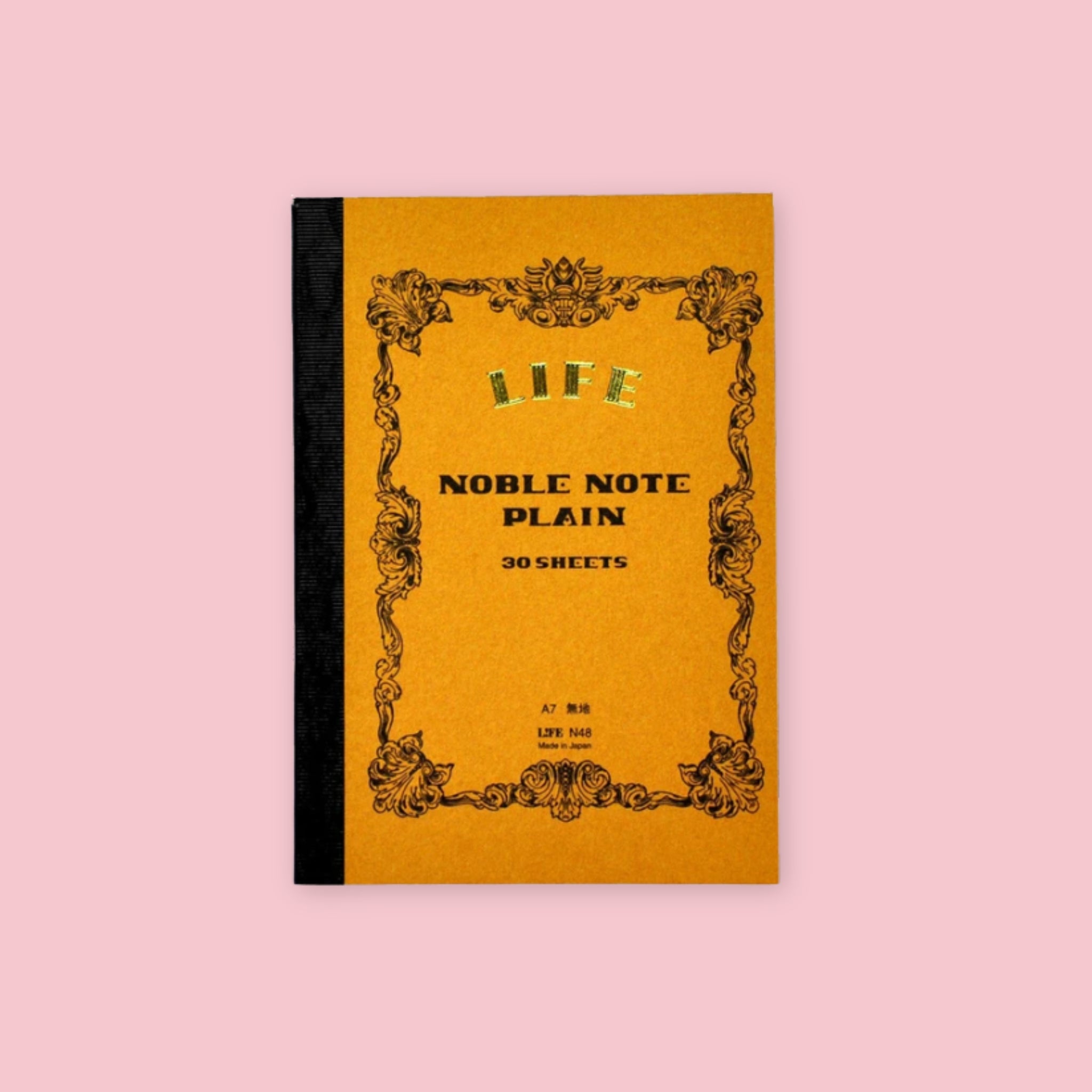 Brown LIFE Noble Note plain notebook with ornate vintage-style black border and black cloth spine on a pale pink background.