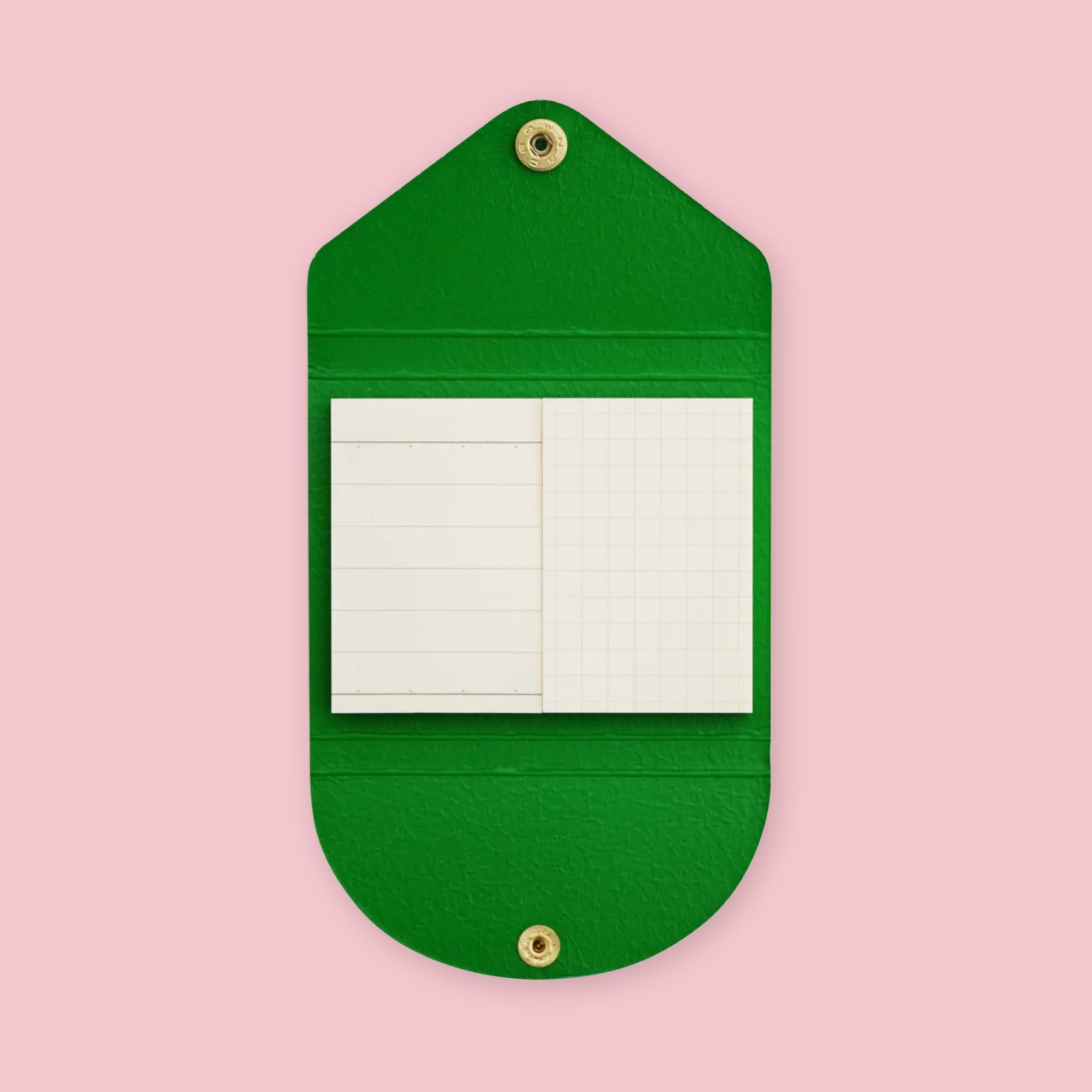 Green faux leather sticky note pouch shaped like an envelope, open to show lined and grid notepads inside, snap closures top and bottom, on a pink background.