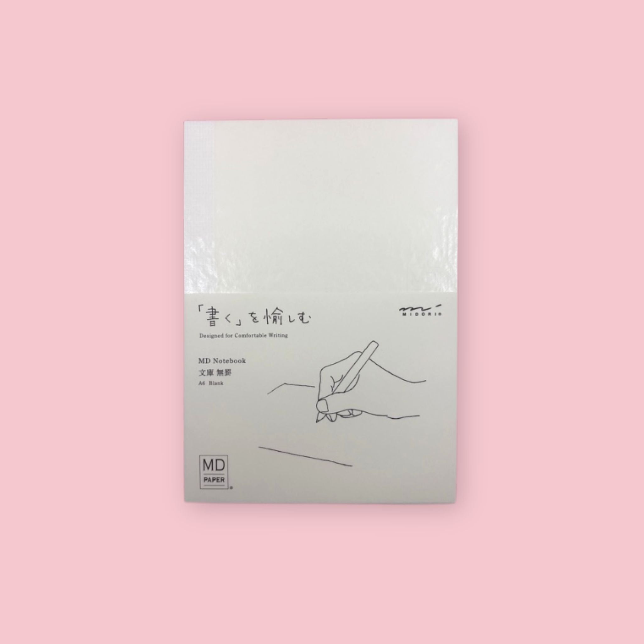 Midori MD Notebook with A6 blank pages and minimalist white cover, photographed against a pastel pink background.