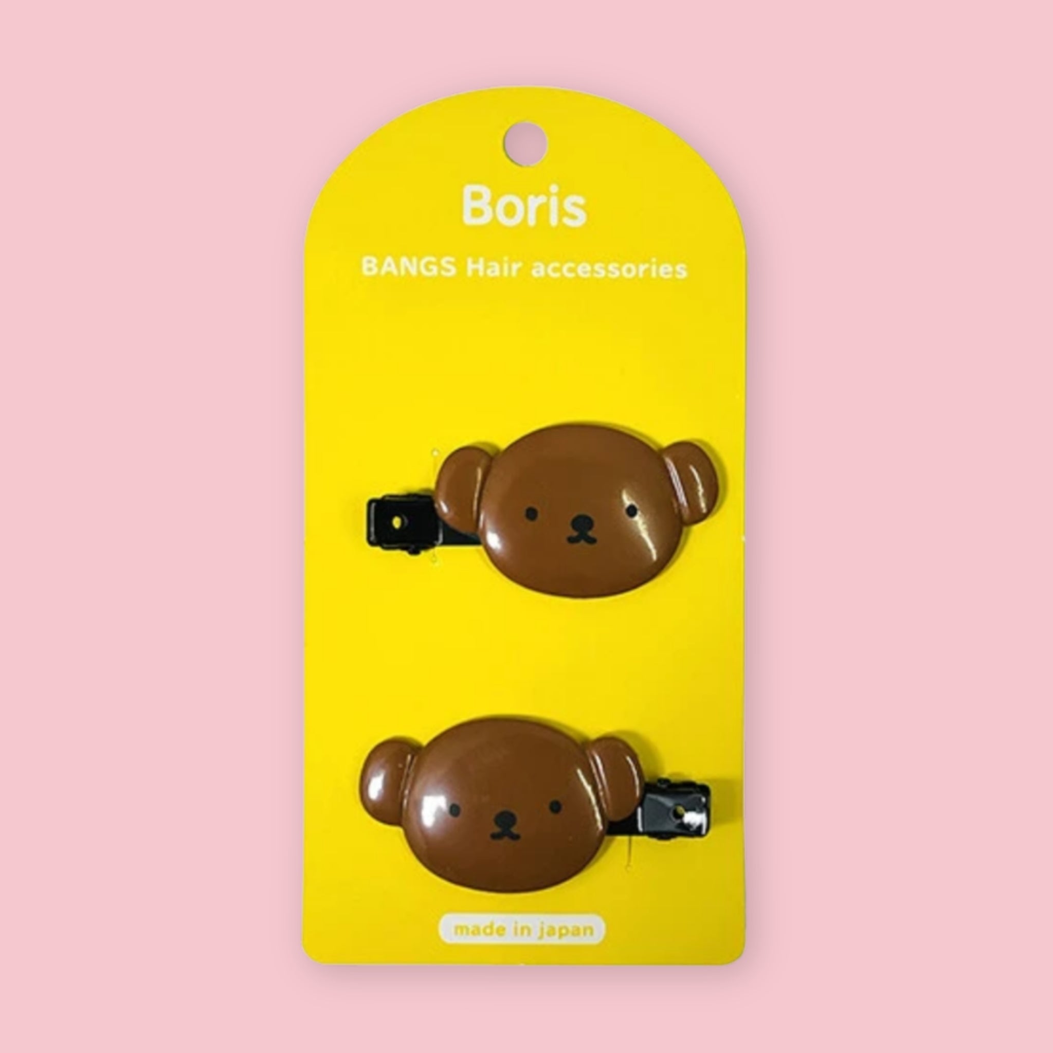 Two brown bear-shaped hair clips on a bright yellow Boris brand card, set against a solid pink background.
