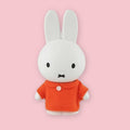 Miffy coin bank in orange outfit on a pink background