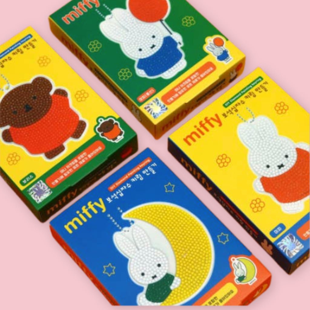 Four Miffy Diamond Painting DIY Keychain Kit boxes laid out on a pink background, showing yellow packaging with Boris the bear and Miffy designs and a blue box featuring the Miffy on the Moon design