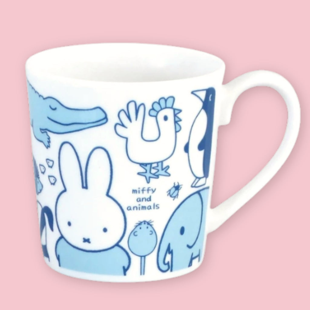 White mug printed with blue "Miffy and Animals" illustrations including Miffy, a crocodile, rooster, penguin, beetle, and elephant, against a pink background