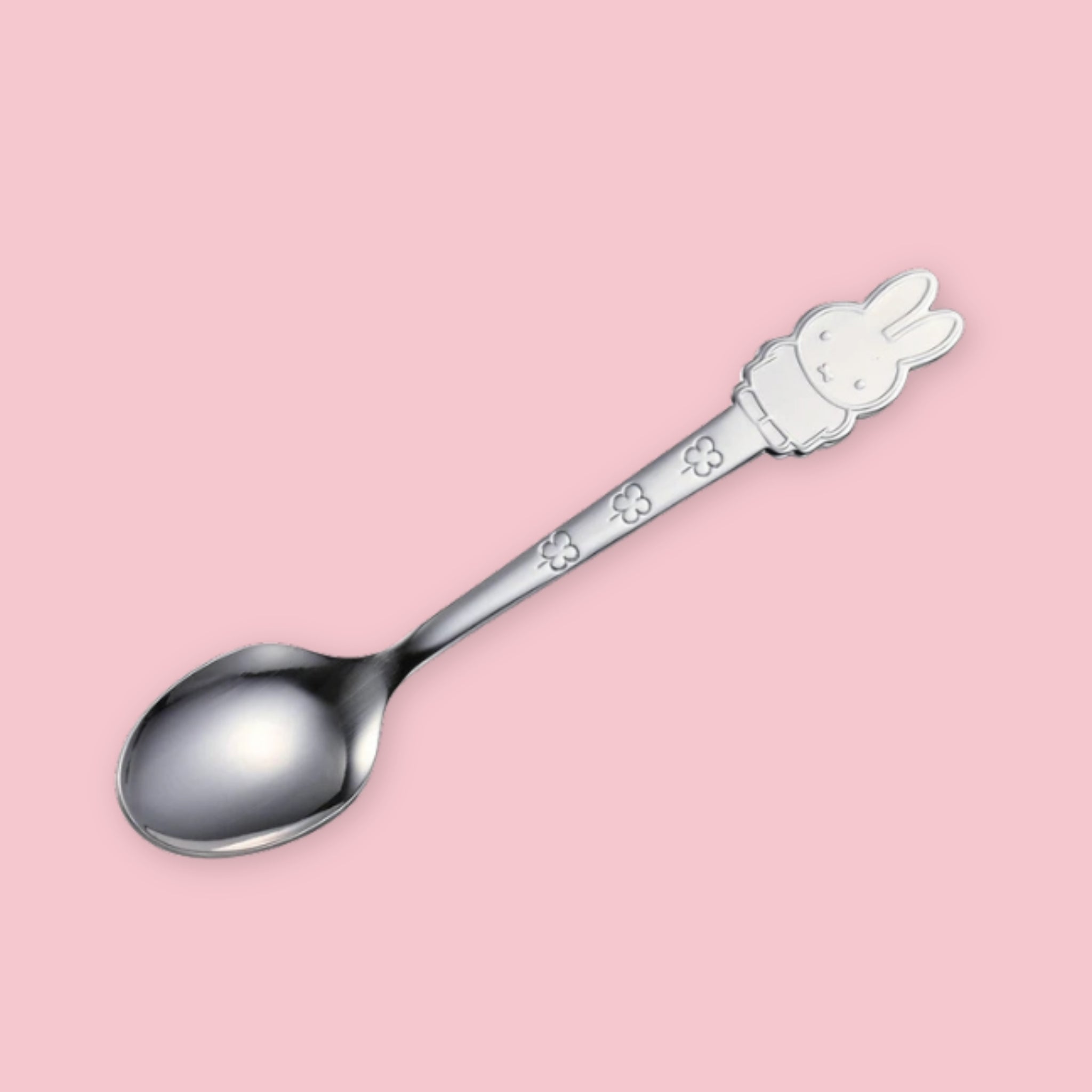A stainless steel spoon with a Miffy character handle topper and floral engraving on the stem, displayed diagonally on a pink background."
