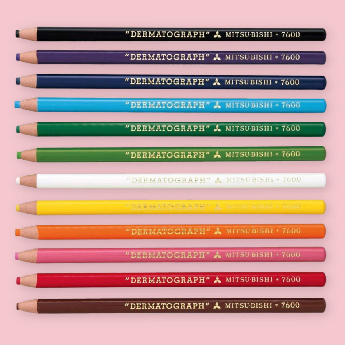 Set of 12 Mitsubishi Dermatograph grease pencils in assorted colors on a pink background.