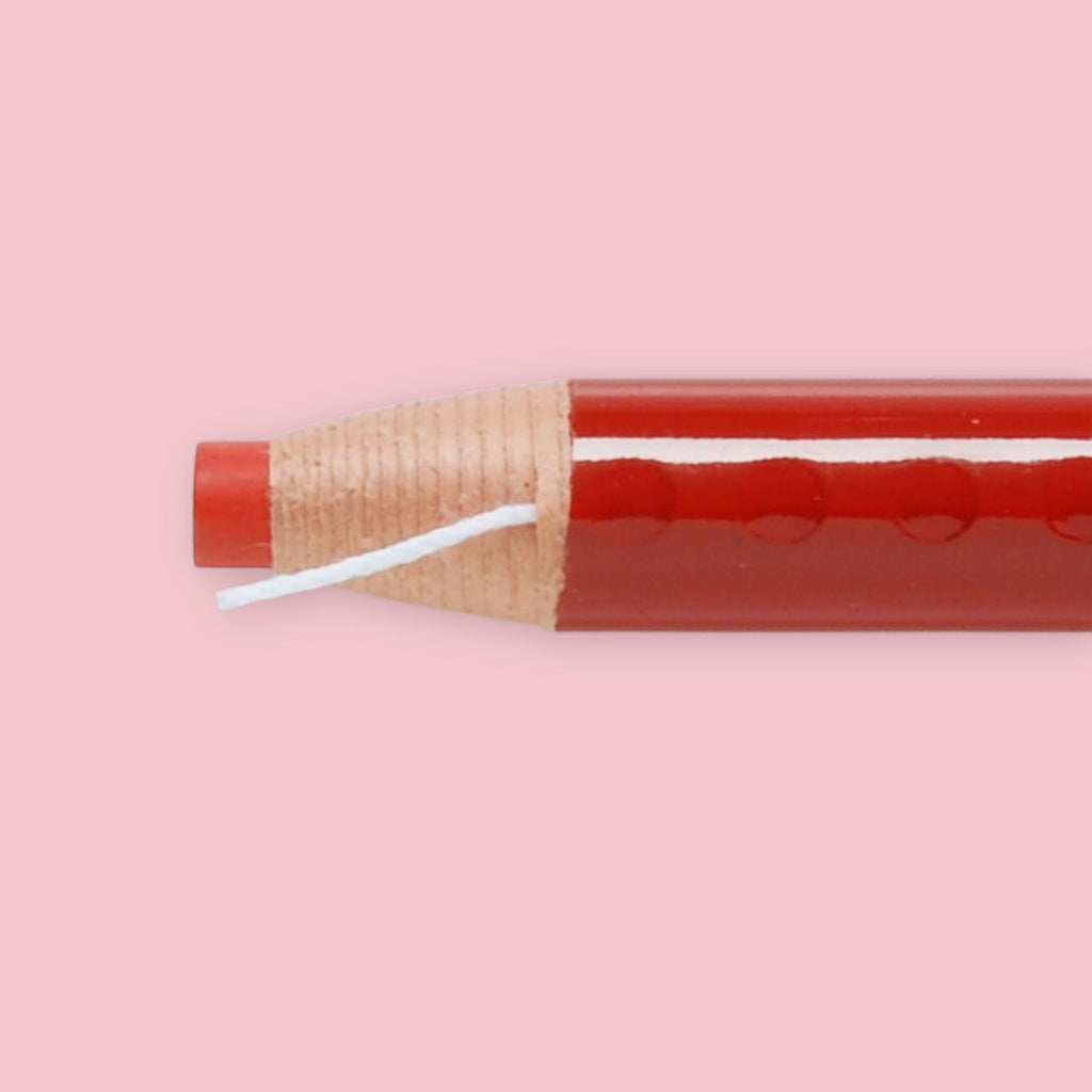 Close-up of red Mitsubishi Dermatograph grease pencil showing the peel-away paper wrapper and pull string.