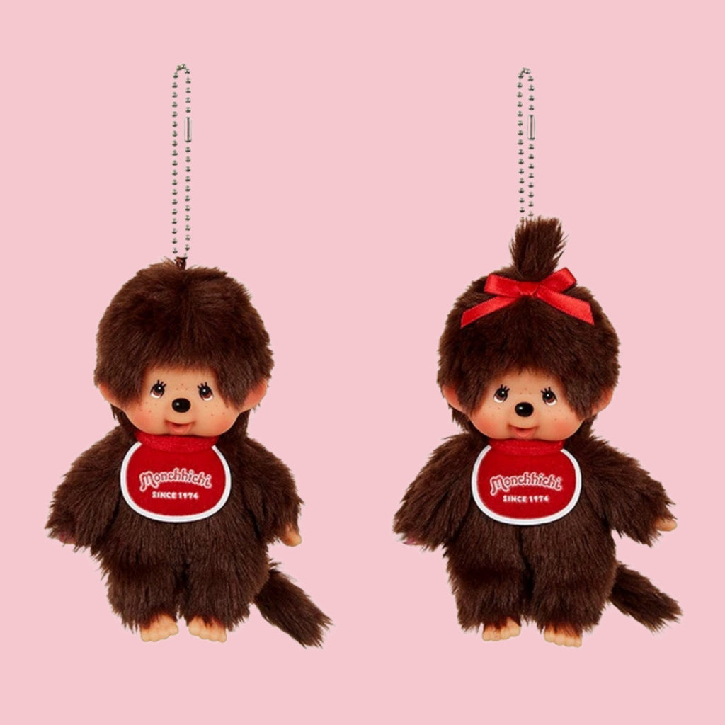 Monchhichi classic brown mascot charms with ball chains, shown in boy and girl styles on a pink background.