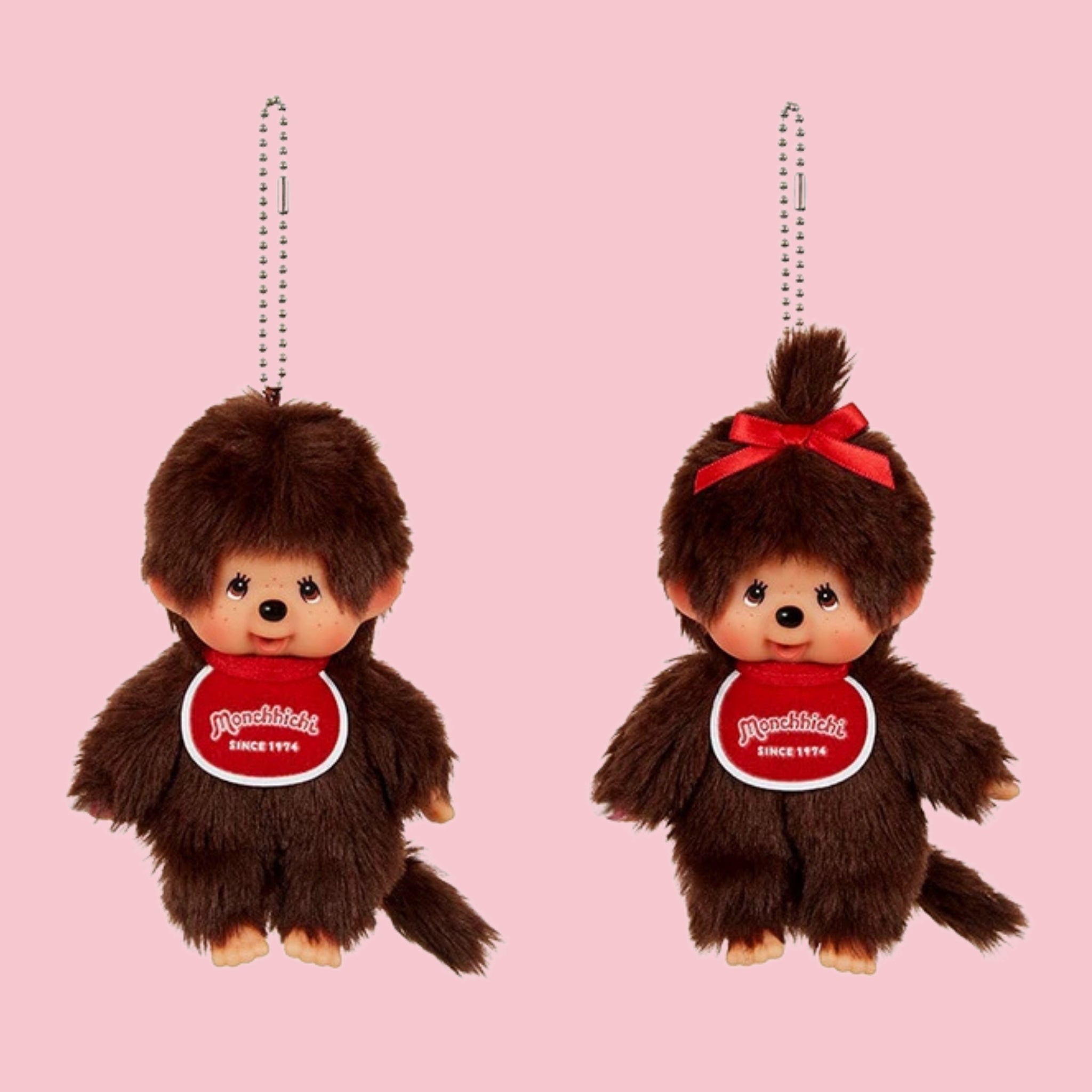 Monchhichi classic brown mascot charms with ball chains, shown in boy and girl styles on a pink background.