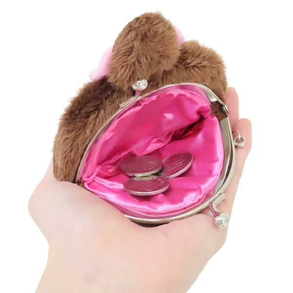 Monchhichi plush coin purse shown open in a hand, with pink satin lining, silver clasp, and coins inside.