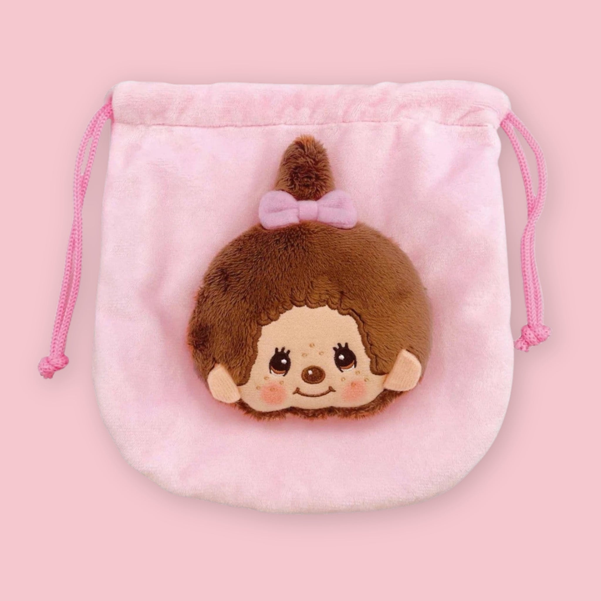 Monchhichi plush drawstring pouch in pale pink, with a soft monkey face and pink bow on the front.