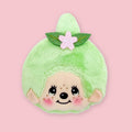 Light green Monchhichi matcha coin pouch with embroidered face and pink flower hair accessory, shown on a pink background.