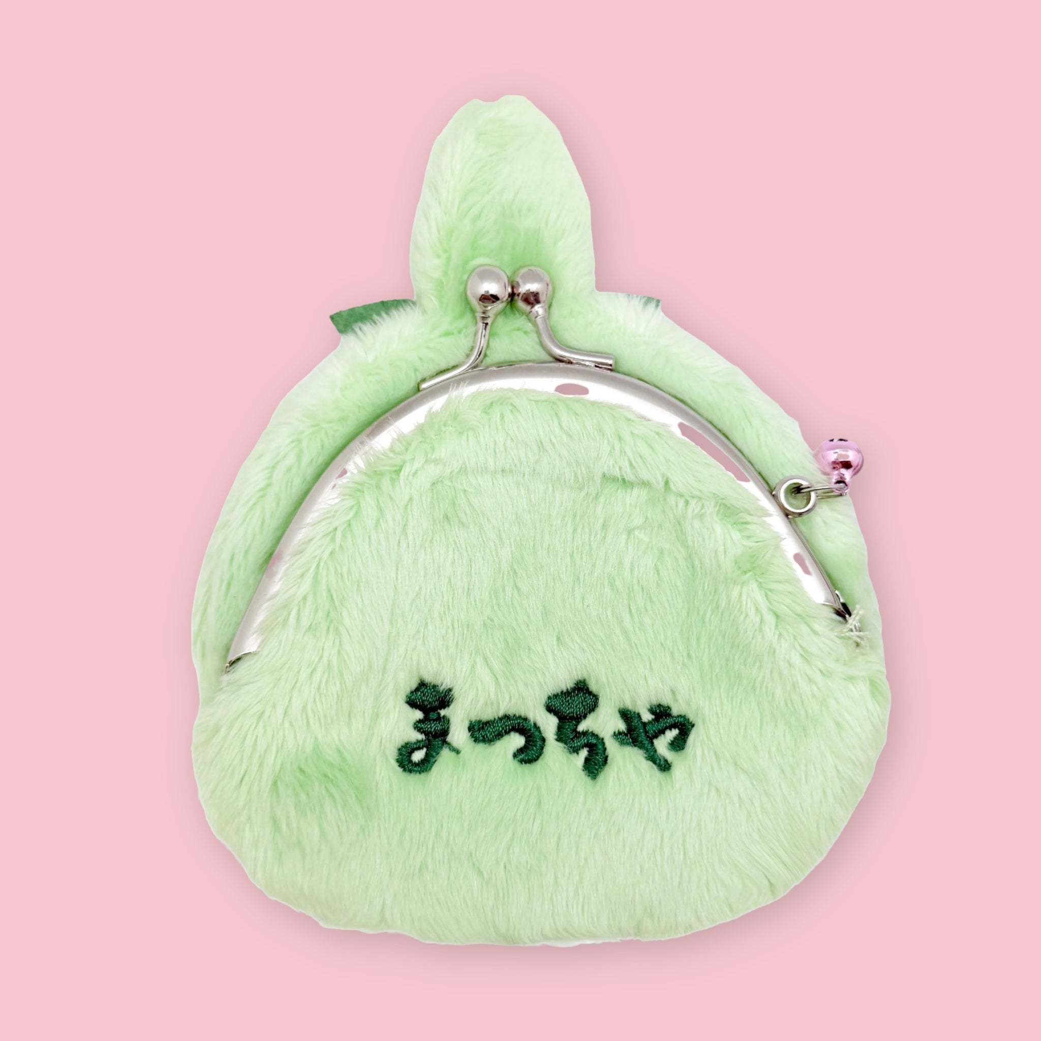 Light green Monchhichi matcha coin purse with silver kiss-lock clasp and embroidered Japanese text on the back, shown on a pink background.