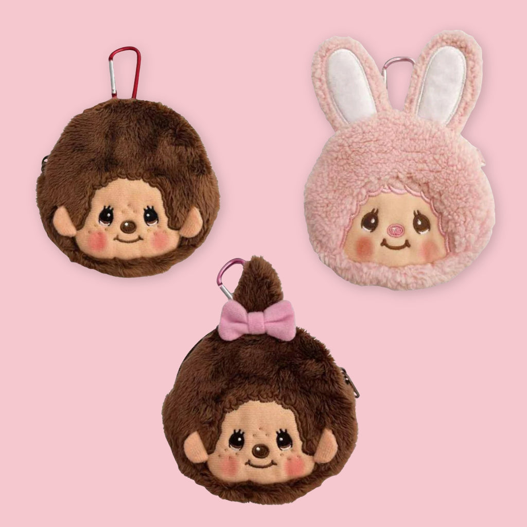Three Monchhichi mini pouches with carabiner clips: Monchhichi-kun, Chimtan in pink with rabbit ears, and Monchhichi-chan with a pink bow, against a pink background