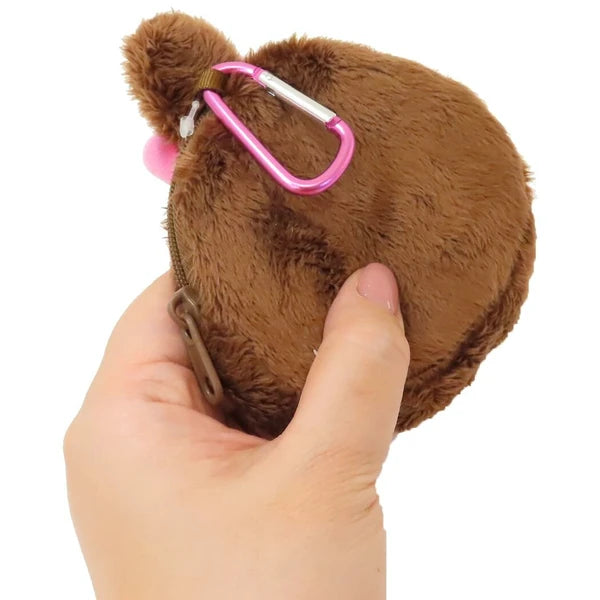 Brown plush toy with a pink carabiner held by a hand on a white background