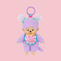 Purple Monchhichi Sweet Lollipop plush keychain with white pigtails, mint bows, and a pink candy bib on a pastel pink background.