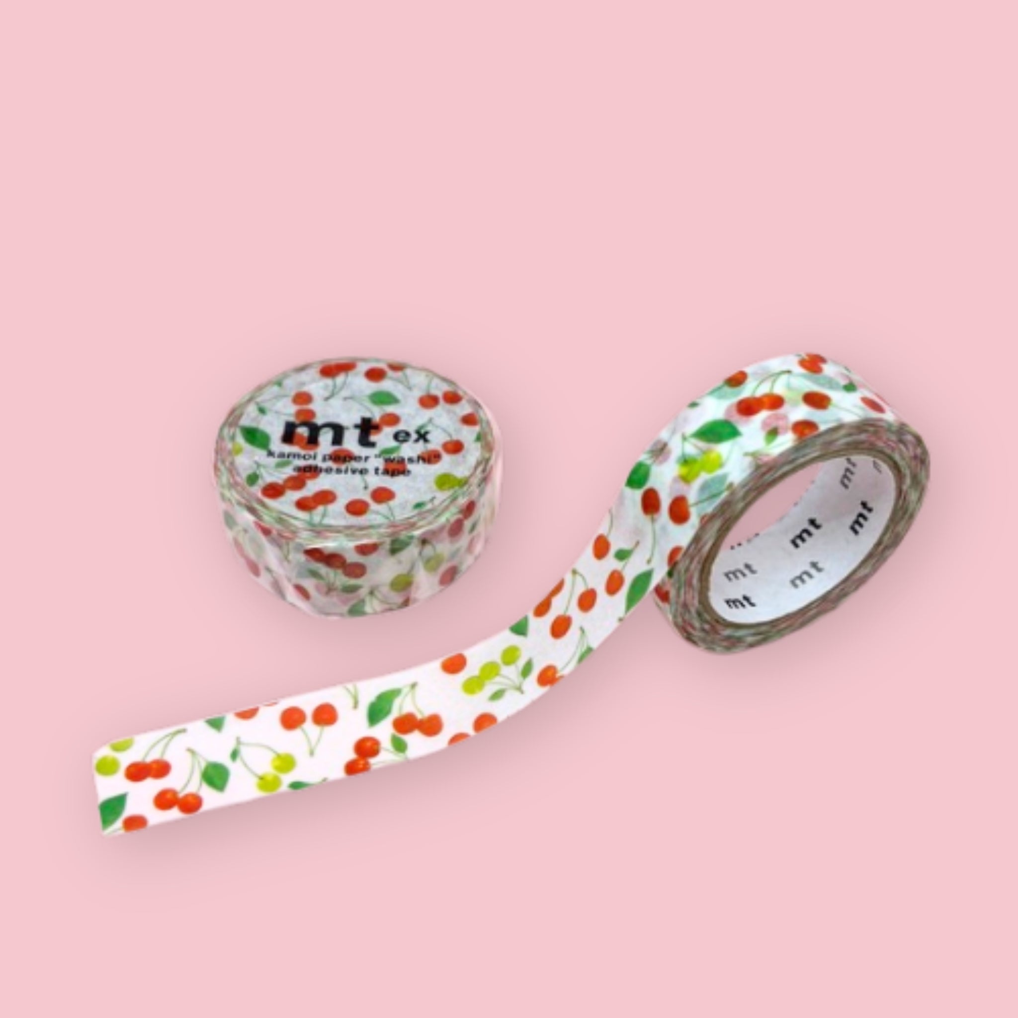 Two rolls of mt ex washi tape with red and yellow cherries and green leaves on a white background, photographed on pastel pink.