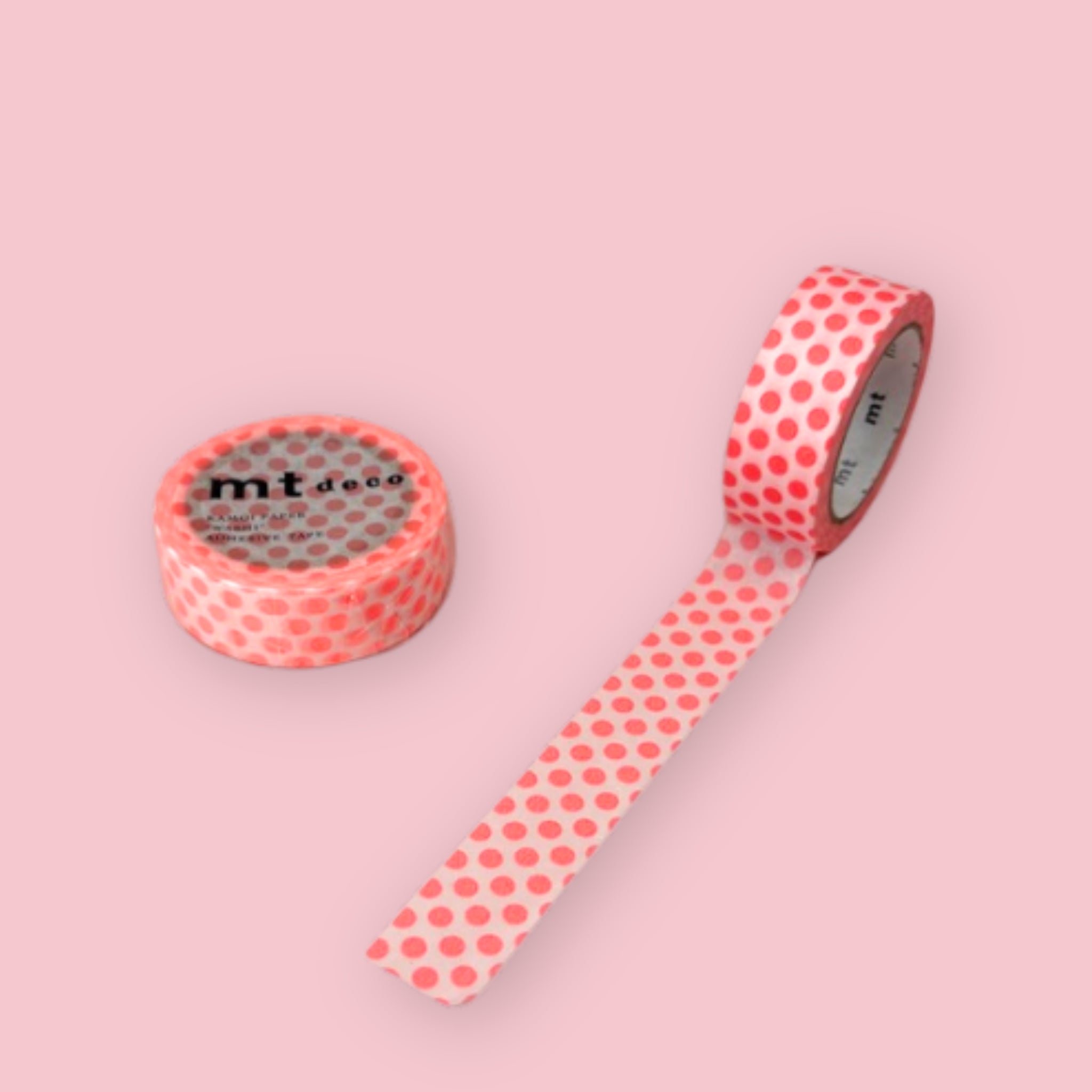 Two rolls of mt deco washi tape featuring a shocking red polka dot pattern on a white background, displayed on a pink surface — one roll standing upright showing the label, one partially unrolled diagonally