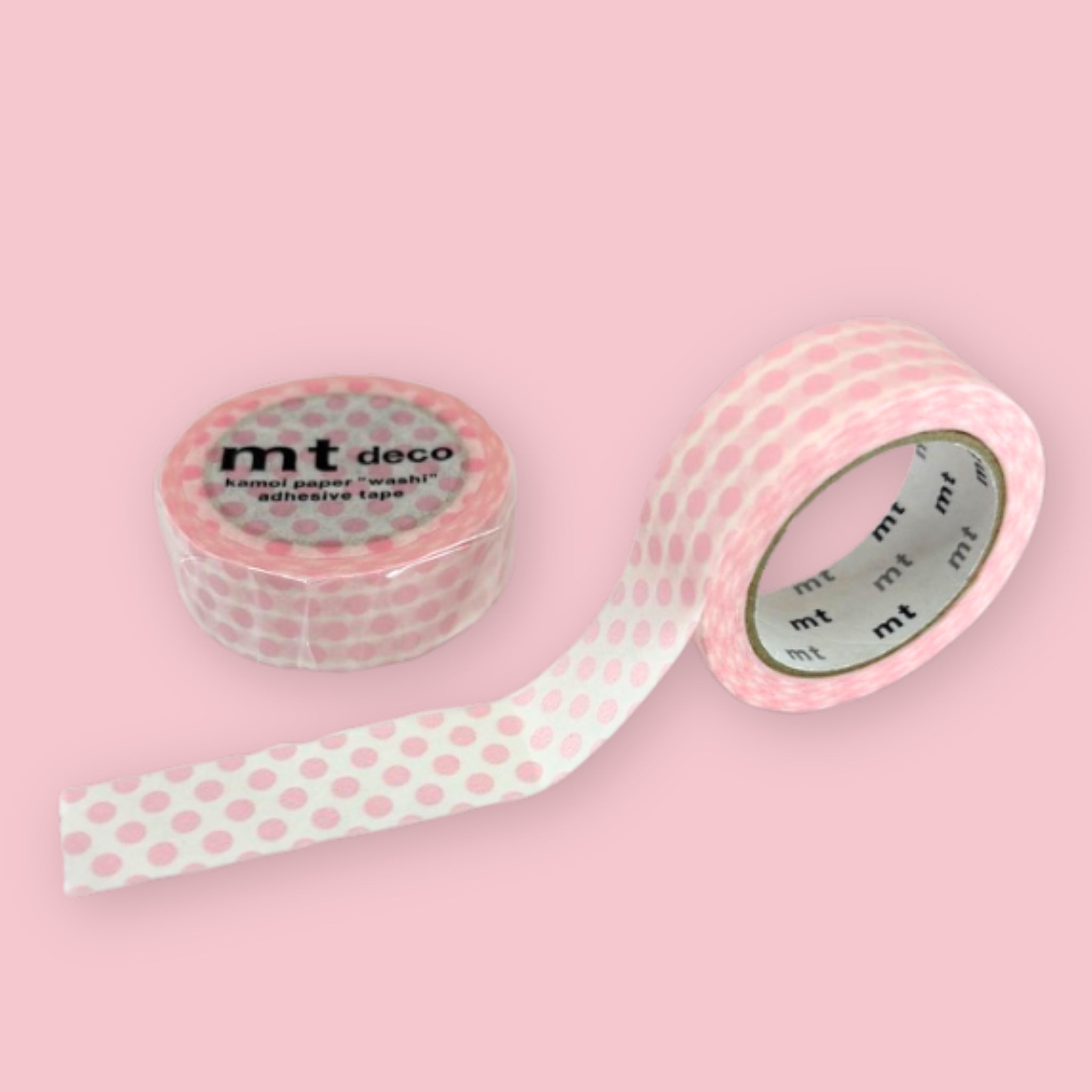 Two rolls of mt deco washi tape with a pale pink polka dot pattern on a white background, photographed on pastel pink.