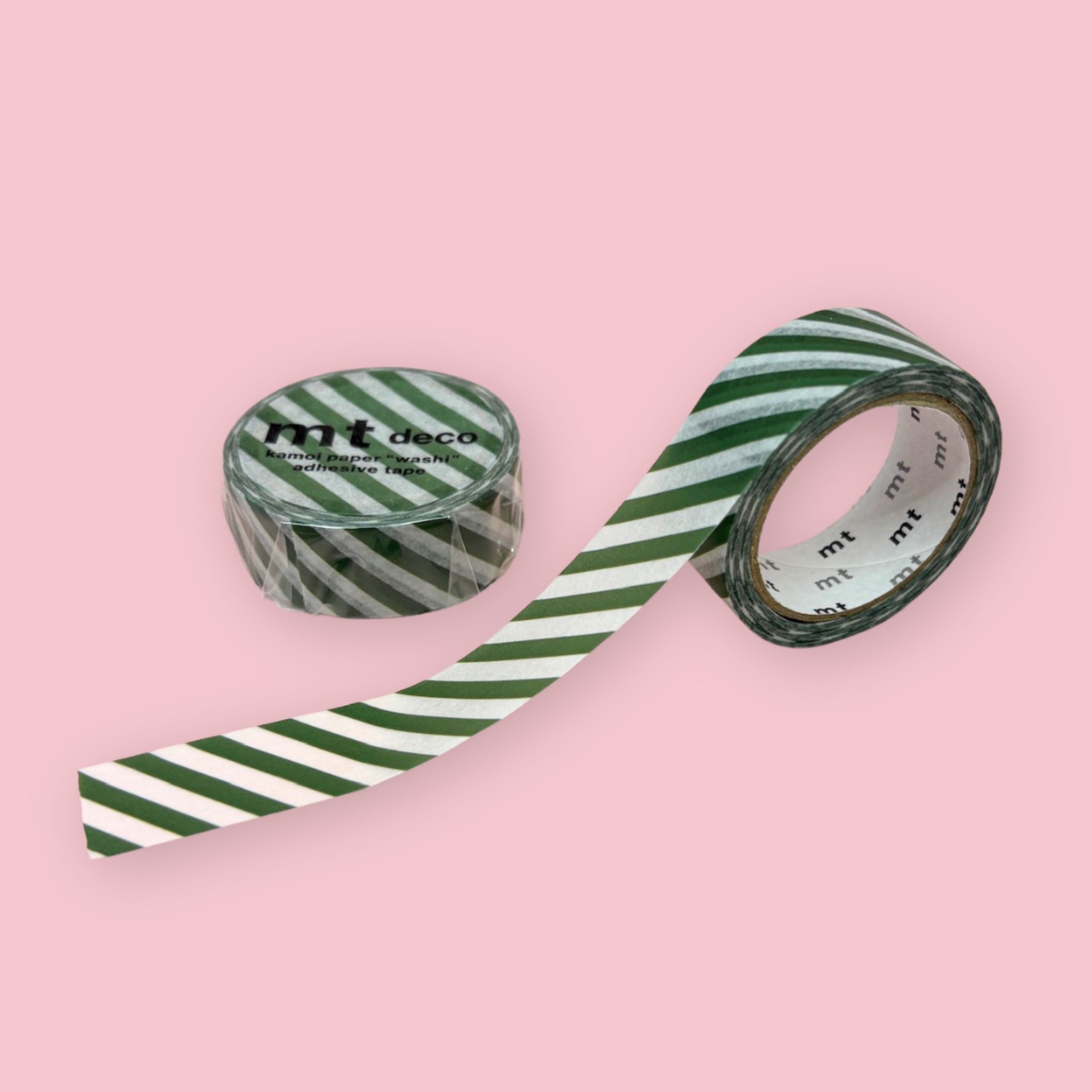 Two rolls of green mt deco washi tape with a white diagonal stripe pattern on a pastel pink background.