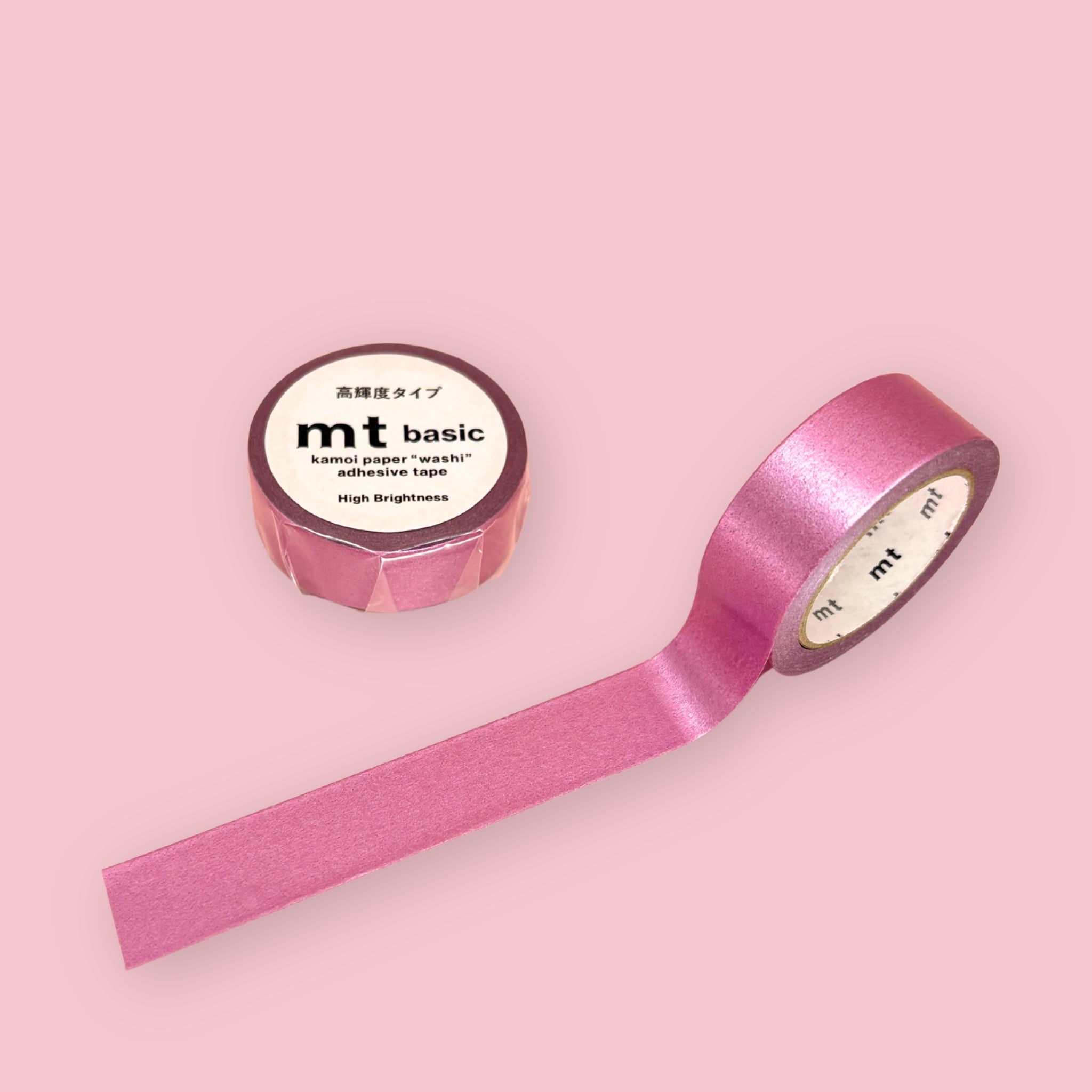 Pink metallic mt basic washi tape with high-brightness label, shown unspooled beside a wrapped roll on a pink background.