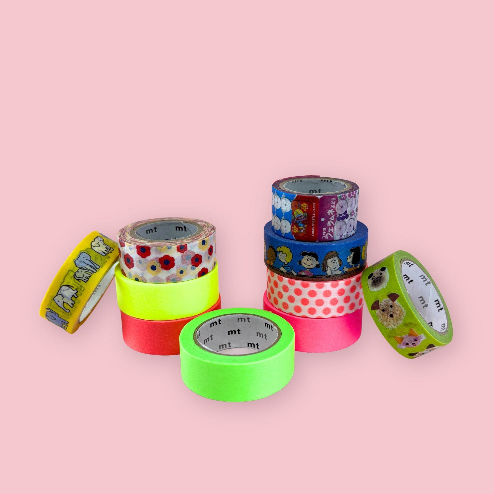 Ten rolls of mt brand washi tape stacked and scattered on a pink background in bright neon and novelty designs
