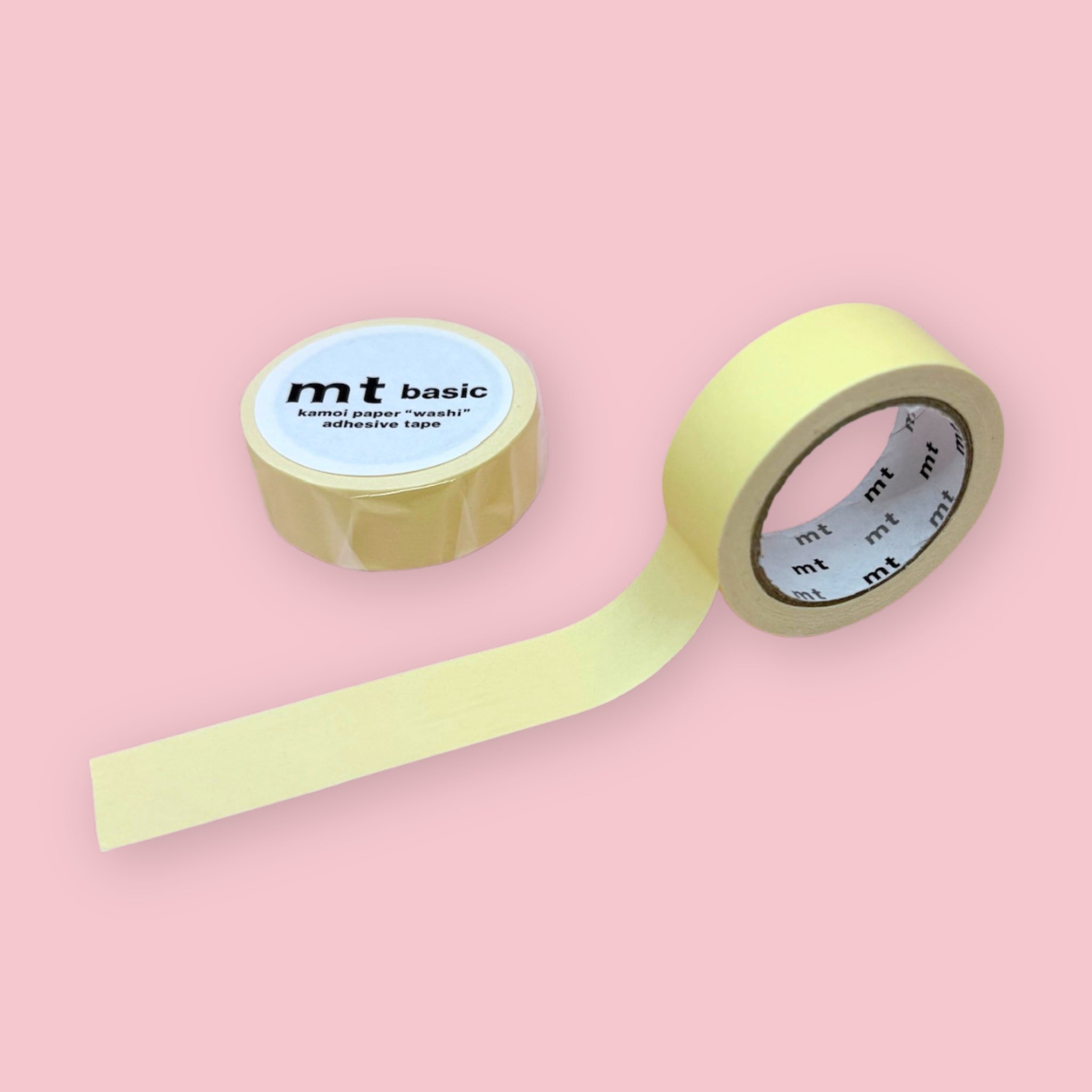 Pastel sunflower yellow mt basic washi tape, shown partly unspooled beside a wrapped roll on a pink background.