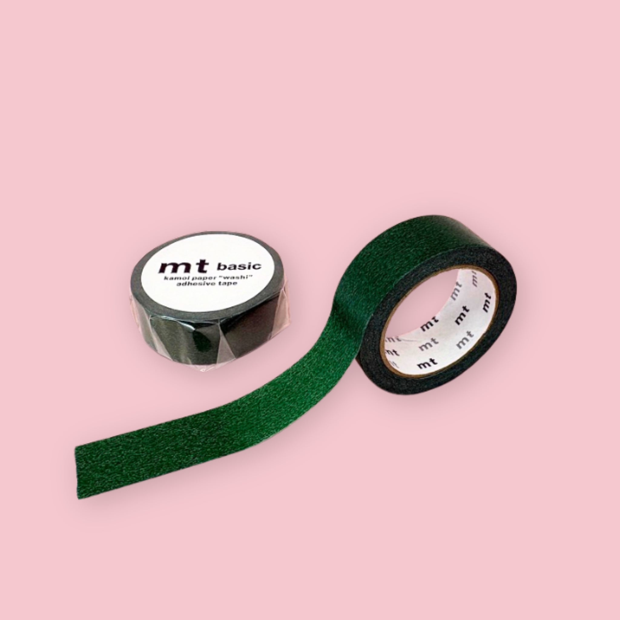 Two rolls of dark green mt basic washi tape on a pastel pink background. One unrolled and one in its packaging. 