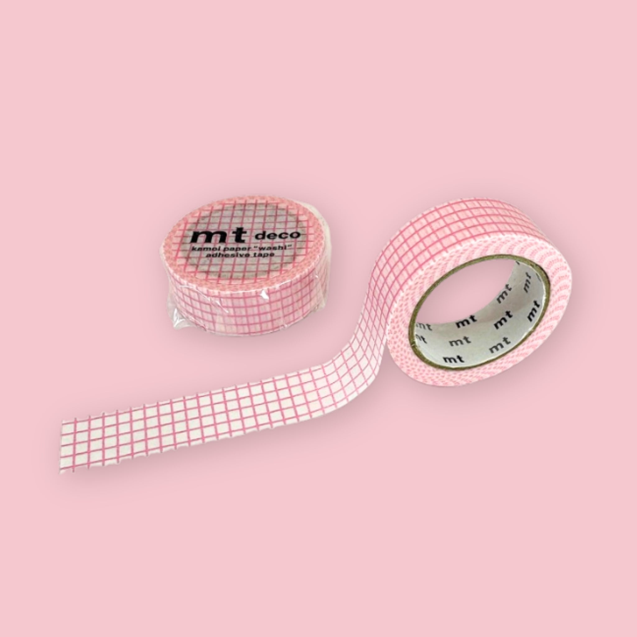 Two rolls of mt deco washi tape with a pink grid pattern on a white background, photographed on pastel pink.