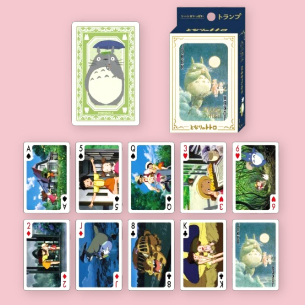 Studio Ghibli My Neighbor Totoro playing cards with card box and a card back design featuring Totoro with an umbrella, shown alongside an assortment of face cards illustrated with scenes and characters from the film, against a pink background