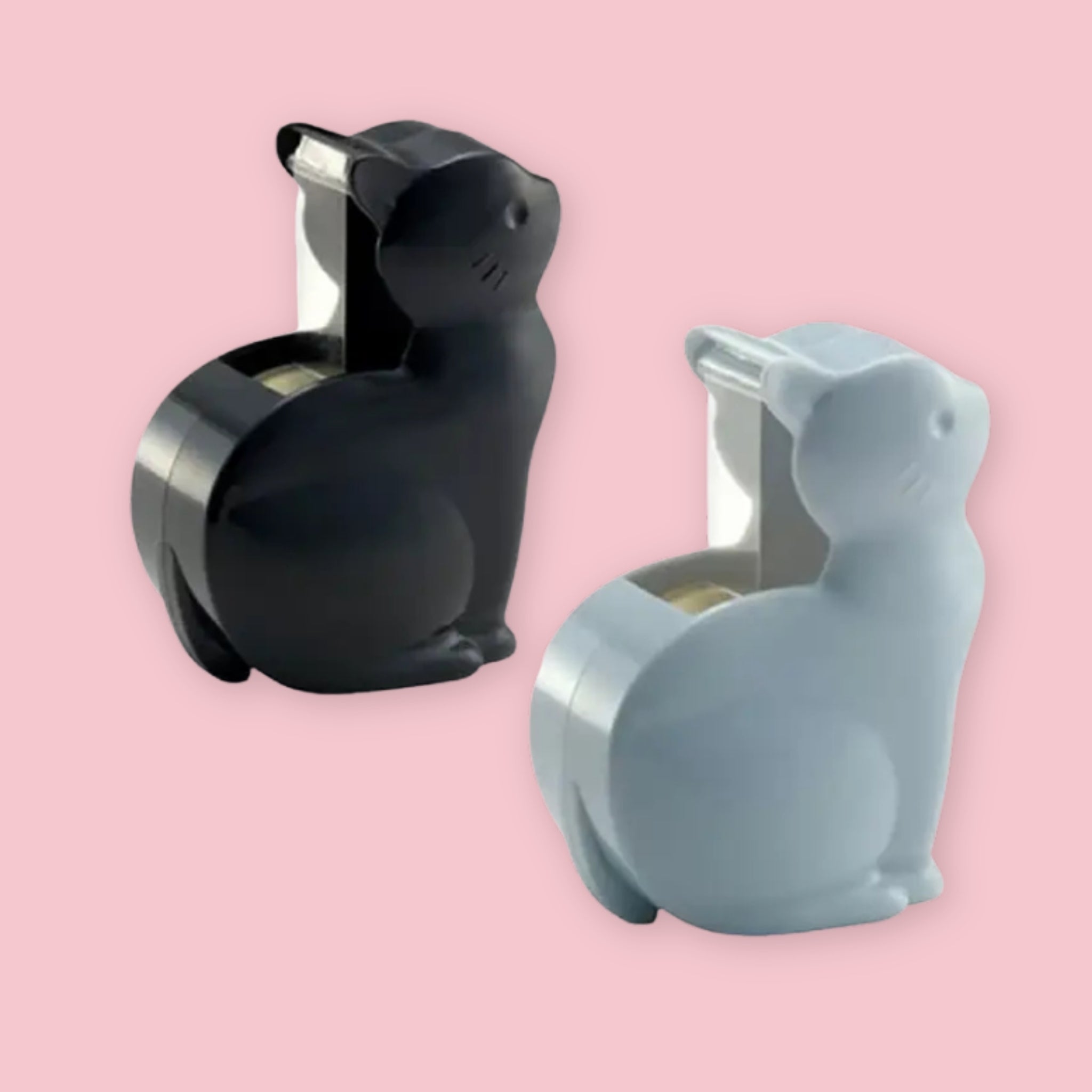 Two cat-shaped tape dispensers, one in matte black and one in gray, shown on a solid pink background.