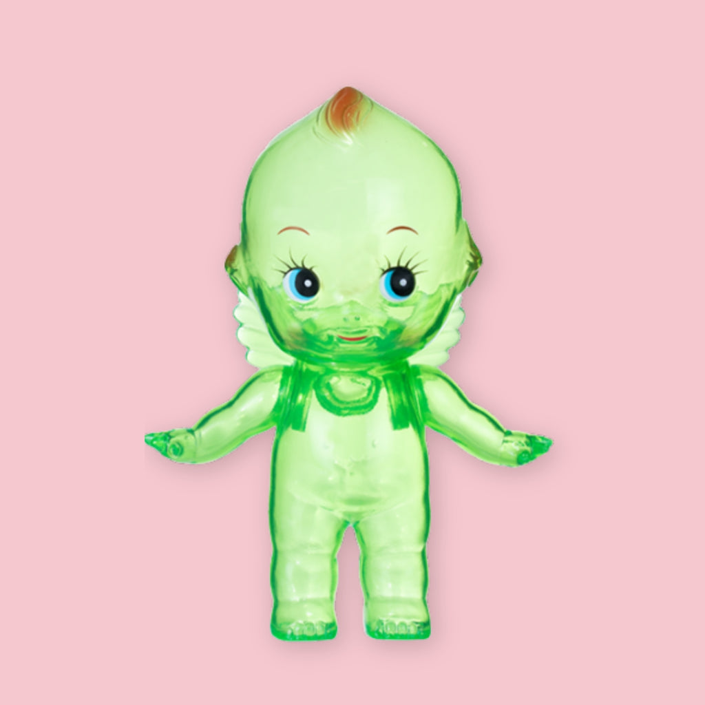 Green translucent Obitsu Kewpie doll with blue eyes, shown standing on a pink background.